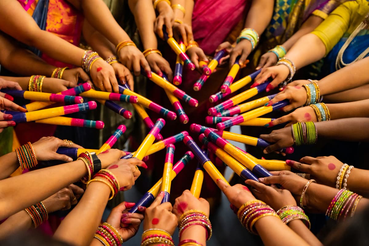 Dancers holding colourful dandiya sticks in a circle at a Garba night